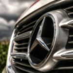 A striking close-up of a shiny Mercedes-Benz car emblem and grille, showcasing luxury.